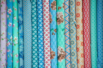 Collection of fabrics at the store counter. View of rolls of fabric in different colors and...