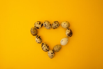 Small quail eggs lie on a yellow background, minimalism for advertising