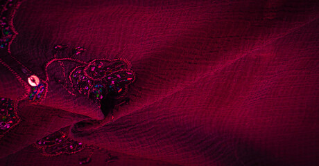 Silk red. The fabric is embellished with sequins. background, silk satin, luxurious texture, dark...