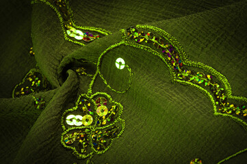 Silk green. The fabric is embellished with sequins. background, silk satin, luxurious texture, dark...