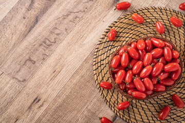 Fresh cherry tomatoes over wooden table background.