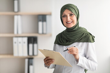 Happy Muslim Female Doctor Posing Standing In Modern Clinic Office