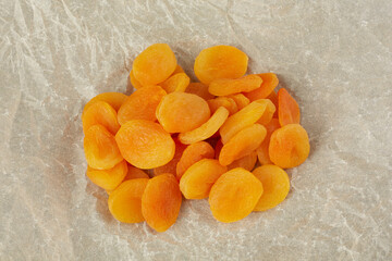 A handful of dried apricots lie on crumpled light paper
