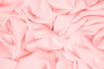The fabric is silk of a pale red color. Texture. Background. Pattern. Silk fabric has a shiny sheen...