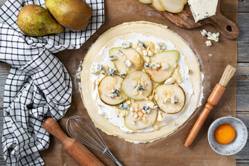 The process of cooking puff pastry pizza with pear, almonds, ricotta gorgonzola or blue cheese on a culinary background. Raw ingredients for layer cake with pear, dorblu, nuts on the table