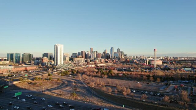 Drone Aerial View Of Downtown Denver Colorado Skyline Flying Over Rush Hour Highway Traffic During Golden Hour Sunset.