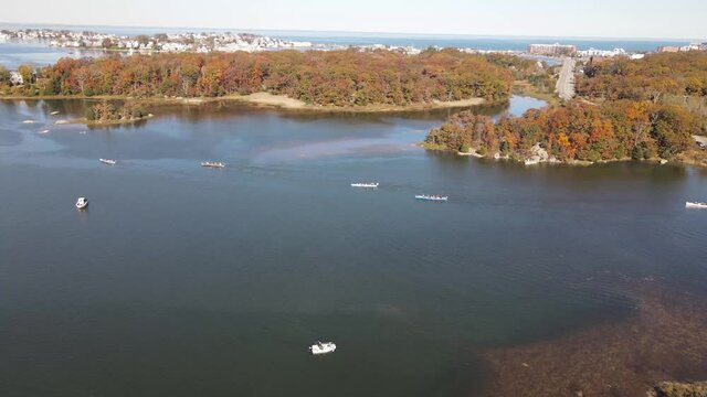 Aerial footage of multiple rowers and boats among islands with Atlantic Ocean in the distance. Static