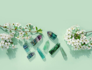 Gemstones minerals set of green colors and white flowers on green background. Healing stones for...