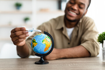 Black Traveler Guy Playing With Airplane Model And Globe Indoor