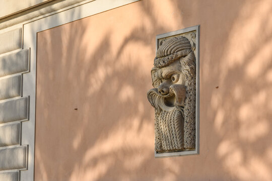 Detail of the exterior wall of a historic villa with a large stone mascaron, Genoa, Liguria, Italy