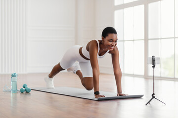 Young black woman exercising in front of smartphone