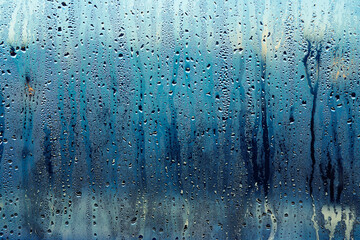 The transparent glass of the window is covered with dripping raindrops. The weather outside the window of the house. Background. - obrazy, fototapety, plakaty