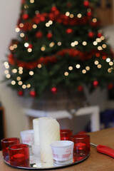 Red and white candles on table in front of Christmas tree.