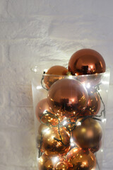 Golden balls with lights in glass vase to decorate interior for Christmas and New Year.
