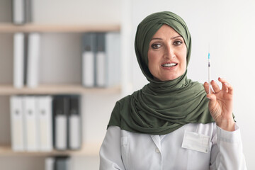 Mature Muslim Doctor Lady Holding Syringe Standing In Clinic