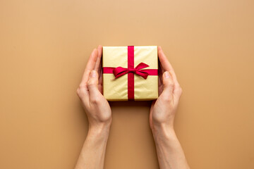 Female hands holding golden gift box - present background