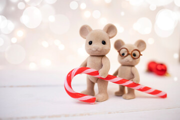 Cute funny mice hold a striped caramel on a blurred background. New Year's composition. Side view, place for text.