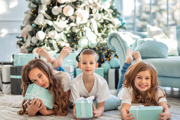 Children at Christmas tree opening presents on Xmas morning.
