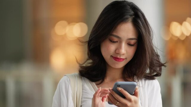 Slow motion of pretty young asian woman using mobile phone in the urban shopping mall