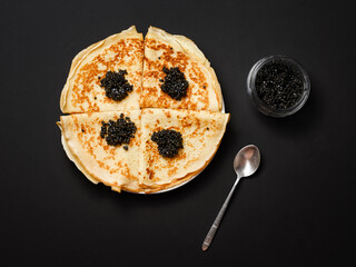 Russian delicacy - natural black sturgeon caviar and thin pancakes - flatlay
