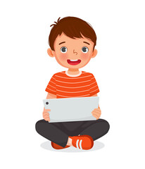 Cute little boy sitting on floor using digital tablet touching screen browsing internet, doing homework, and playing games. Kids and electronic gadget devices concept for children