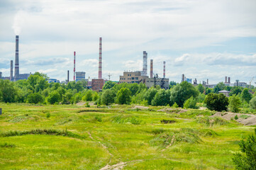 Fototapeta na wymiar City landscape. Large metallurgical enterprise against the background of a dry summer river