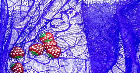 Lace fabric in blue. Plastic strawberries. Decorative strawberries can be sewn onto fabric.   Bright decoration. Texture Background Pattern
