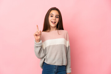 Little girl isolated on pink background thinking an idea pointing the finger up