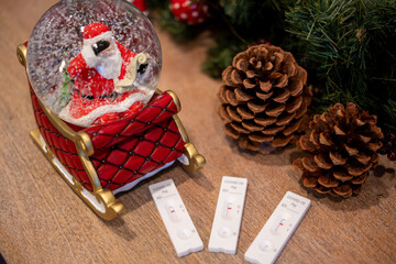 Christmas decoration with a Father Christmas snow ball, pine tree cones and three COVID-19 test strips