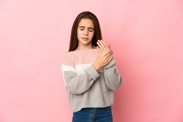 Little girl isolated on pink background suffering from pain in hands