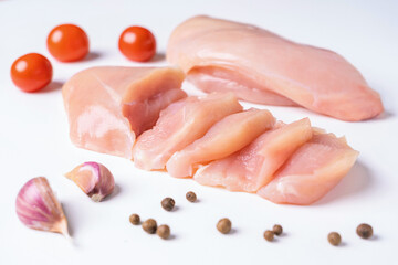 Raw chicken breast, chicken fillet cut into slices with garlic, cherry tomatoes and pepper side by...