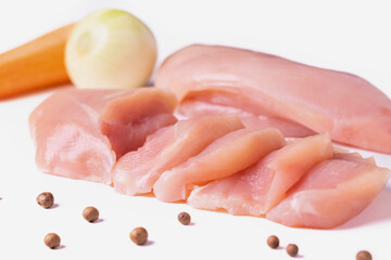Raw chicken fillet cut into slices. Chilled chicken breast, carrots and onions isolated on a white background