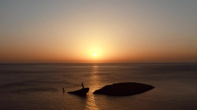 Shipwreck at Diakofti Kythira island Greece. aerial zoom video. Half sunk boat on the sea, at sunset.