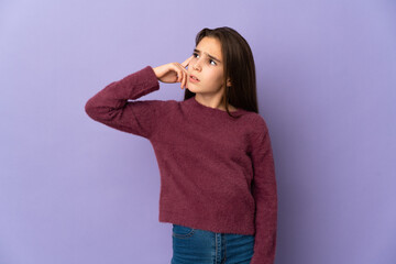 Little girl isolated on purple background making the gesture of madness putting finger on the head