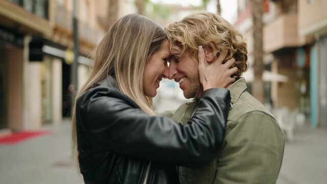 Young caucasian couple kissing and hugging each other at street