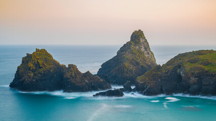 Naklejka premium The coastline of Cornwall, England. A summers evening and the sky is glowing as the sun sets over the spectacular, rugged coastline