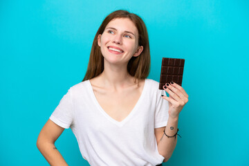 Young English woman with chocolat isolated on blue background posing with arms at hip and smiling