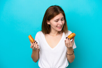 Young English woman isolated on blue background holding donuts with happy expression