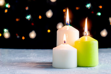 black Christmas background with colorful lights and burning candles in the foreground