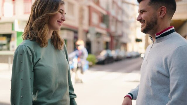 Young couple smiling confident with hands together at street