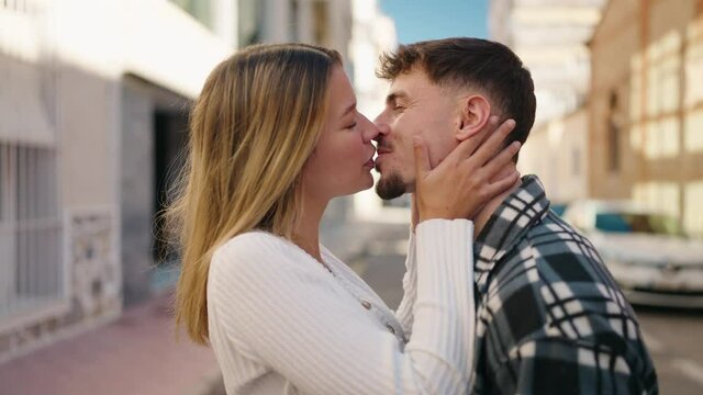 Young couple kissing and hugging each other standing at street