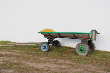 a wooden cart with wheels from a car at the wall of a barn in a Russian village