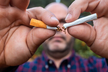 Caucasian man breaking a cigarette in front of the camera.