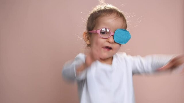 Baby girl 3 years old wearing glasses and an occluder  to prevent astigmatism, amblyopia and strabismus (squint, lazy eye). She is happy.
