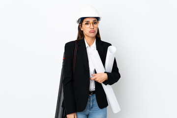 Young architect caucasian woman with helmet and holding blueprints over isolated background sad