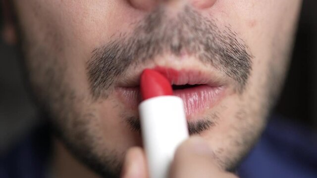 Queer Man With Beard Applying Red Lipstick on His Lips Closeup