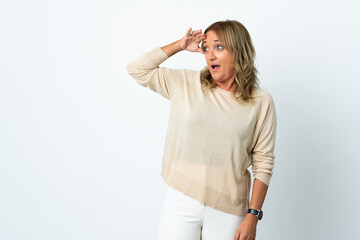 Middle aged blonde woman over isolated white background with surprise expression while looking side