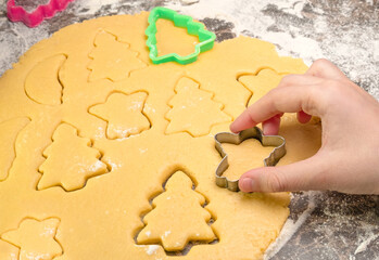 Kids hand with form of christmas cookies for children, making gingerbread in form of man. New year treat for Santa Claus cooking. Raw dough. Homemade bakery, xmas sweet, winter holidays concept