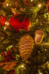 Decorations on a christmas fir-tree: shiny red ball,  golden cone and golden acorn on the blurred christmas background