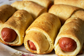Sausages rolls in roasted dough against sky background. Fried pies with sausages. They are wrapped in thin strips of butter dough.